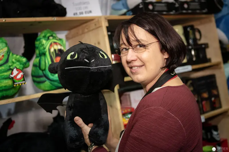 Plush Toothless Dragon and Smiling Staff Member at Comic Convention