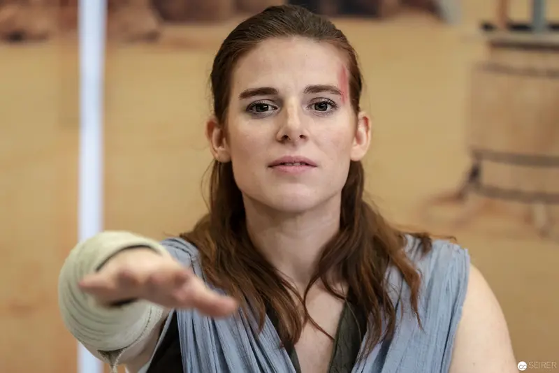 Woman in Blue Vest Extending Hand with Intense Gaze at Vienna Event