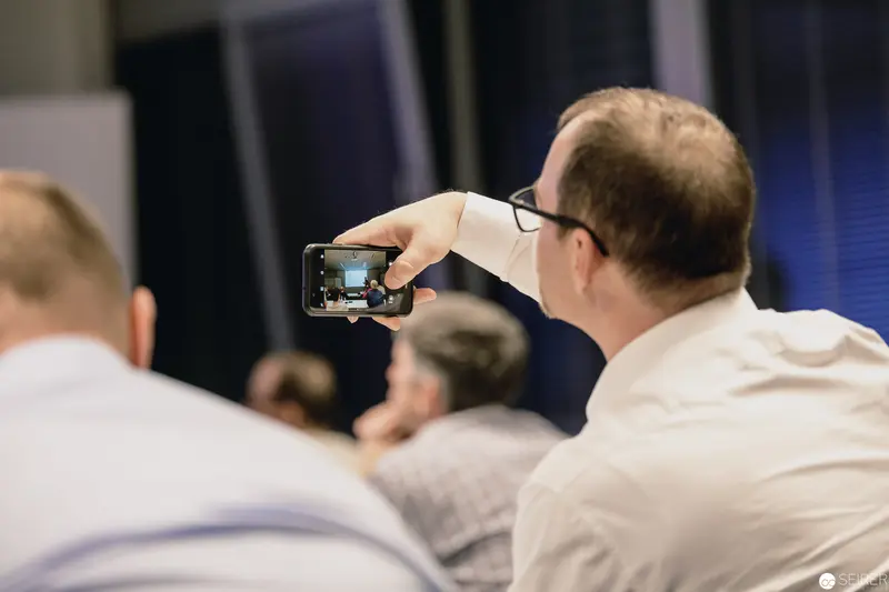 Conference Participant Documenting Presentation Using Smartphone Camera