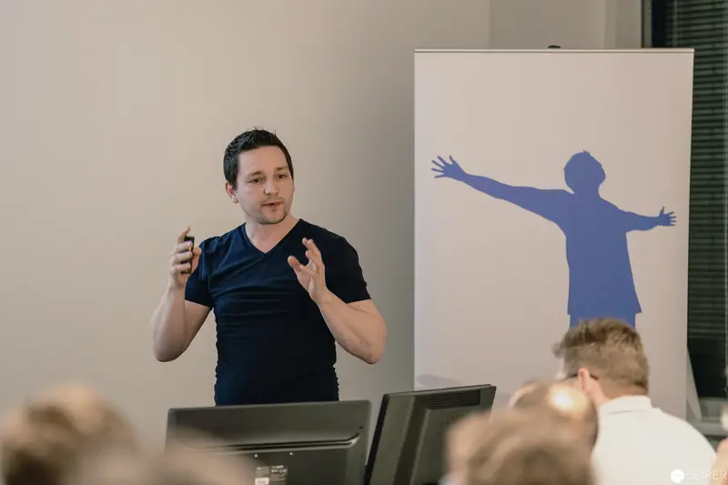 Speaker Gesturing During Presentation with Blue Silhouette Backdrop