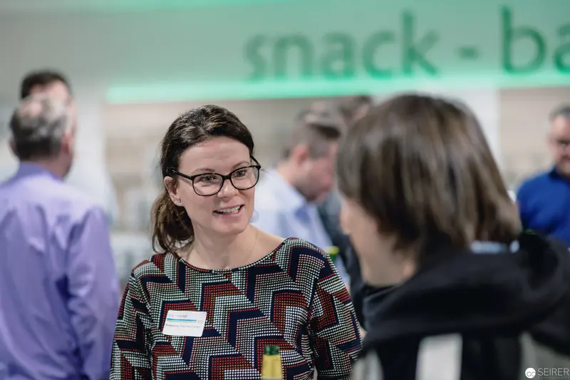 Professional Networking Event with Smiling Participant in Geometric-Print Blouse