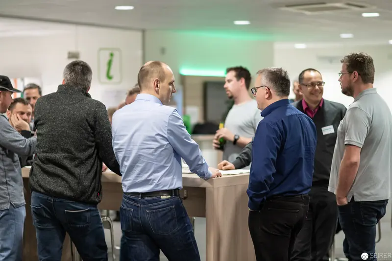 Corporate Networking Event: Professionals Engaged in Conversation at Information Counter