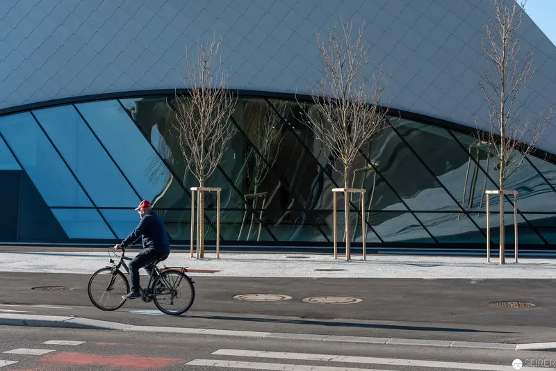 Cyclist Passing Modern Glass Architecture on Urban Bike Lane