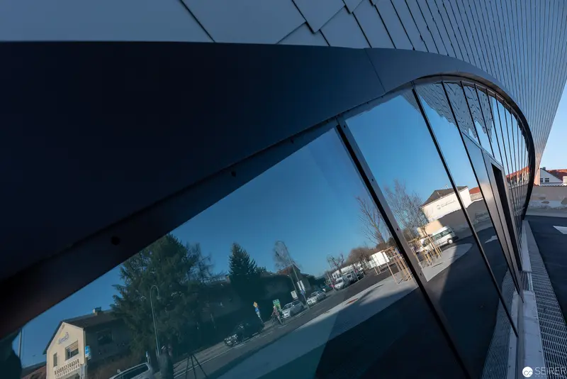 Curved Glass Facade Reflecting Urban Streetscape in Oblique Perspective
