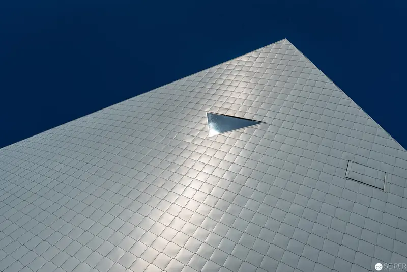 Geometric Metallic Facade with Triangular Accent Against Deep Blue Sky
