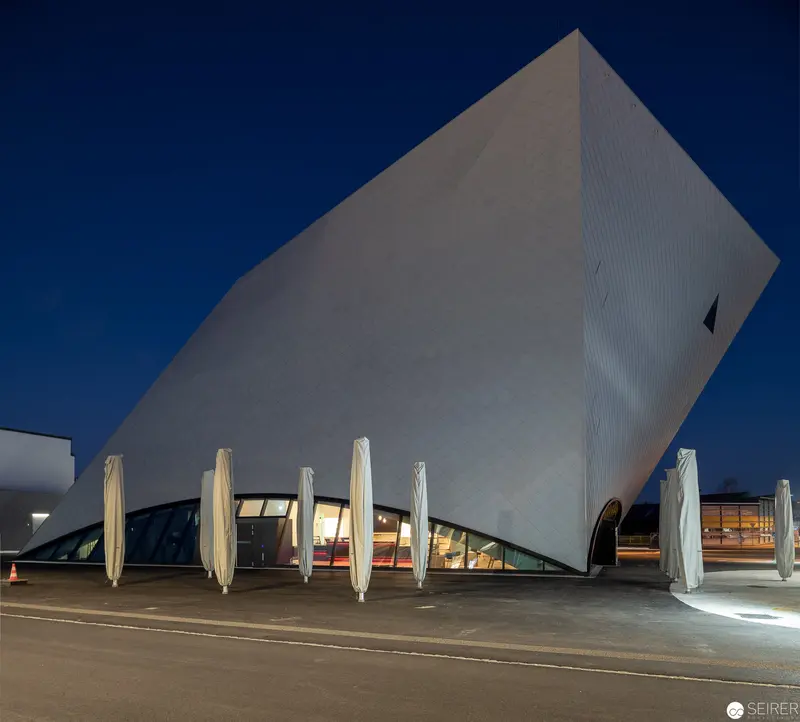 Modern Architectural Volume with Angled Facade and Deployed Umbrellas at Dusk
