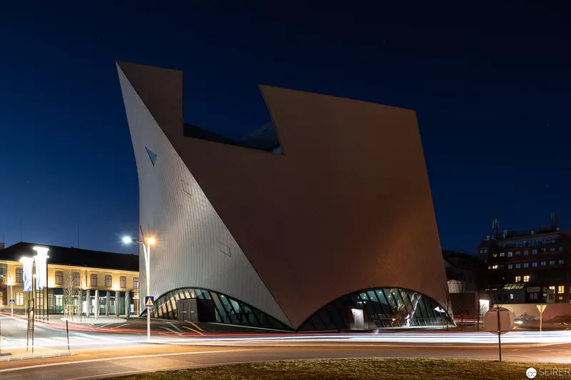 Modern Architectural Form with Dynamic Curved Structure at Nighttime Urban Intersection