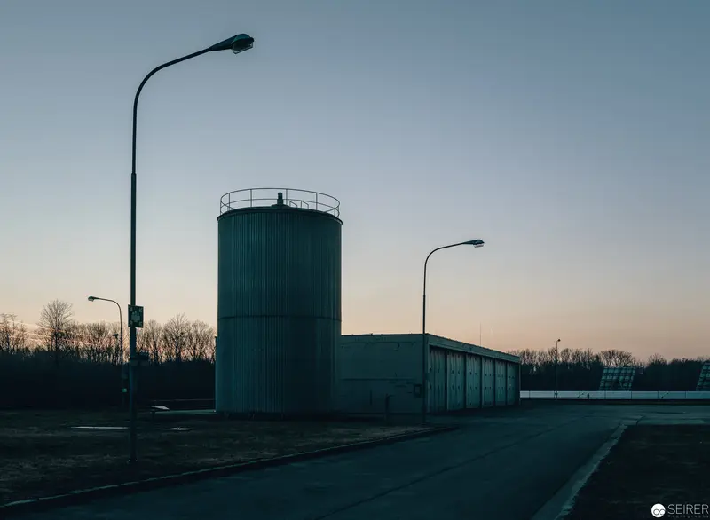 Twilight Industrial Landscape with Water Tower and Street Lamps