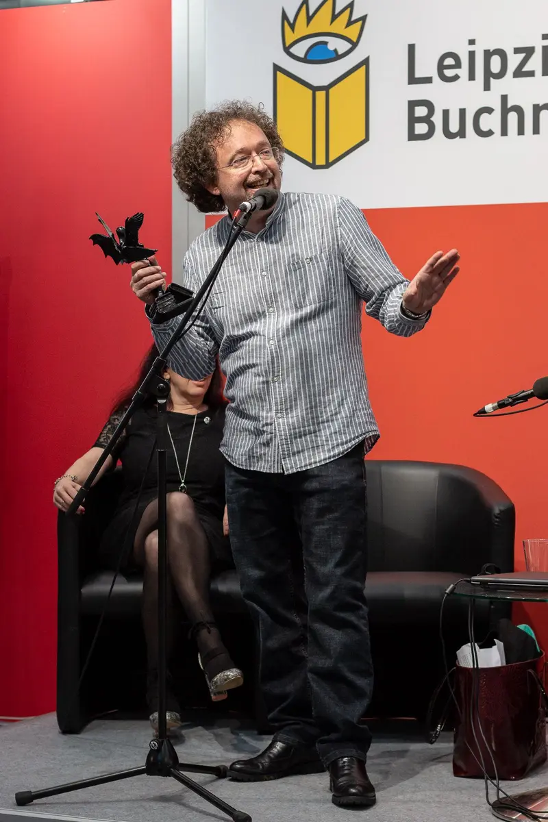 Animated Speaker at Leipzig Book Fair Engaging with Microphone and Gesture