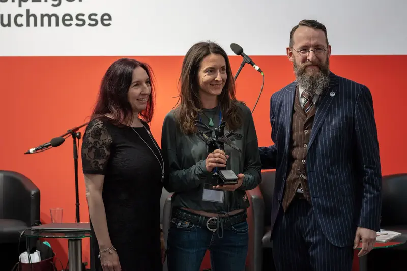 Award Ceremony at Publishing Conference with Three Professionals on Stage