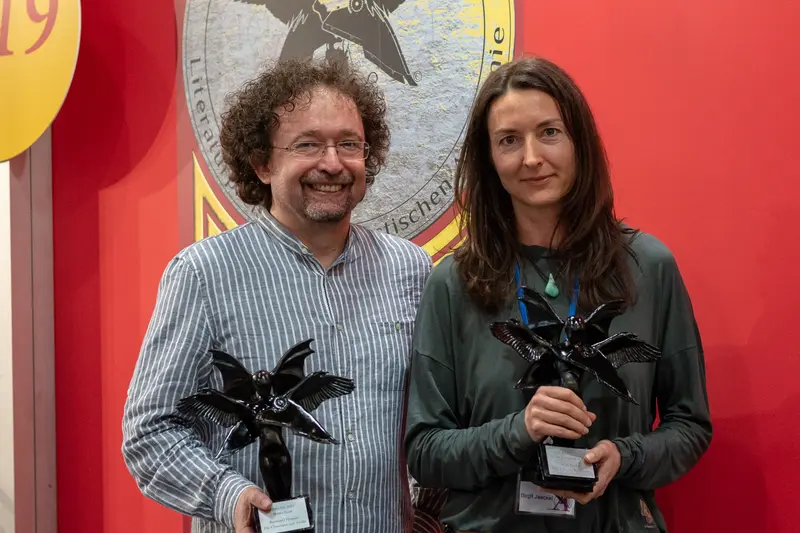 Two Award Recipients Holding Black Star-Shaped Trophies at Ceremonial Event