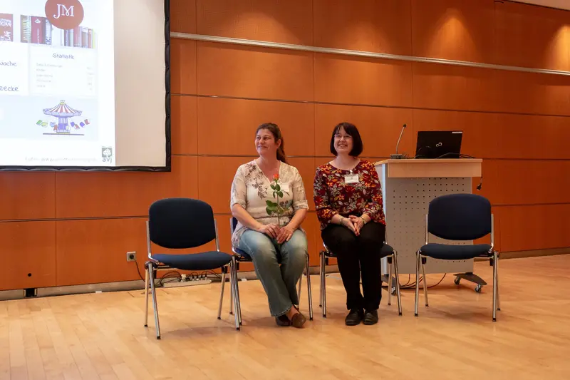 Conference Presenters at Podium: Two Women in Professional Setting