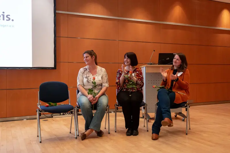 Three Women Panelists Seated on Stage During Conference Discussion