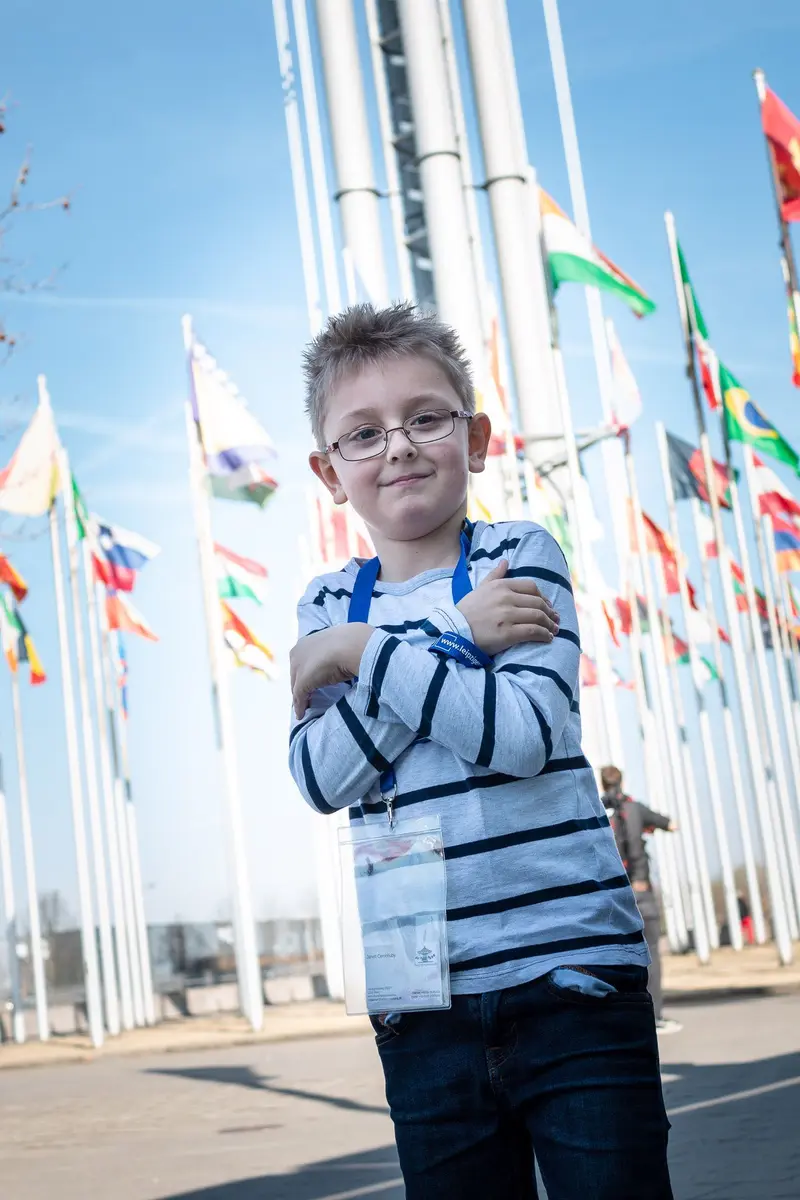 Young Boy Posing Confidently Among International Flags on Bright Day