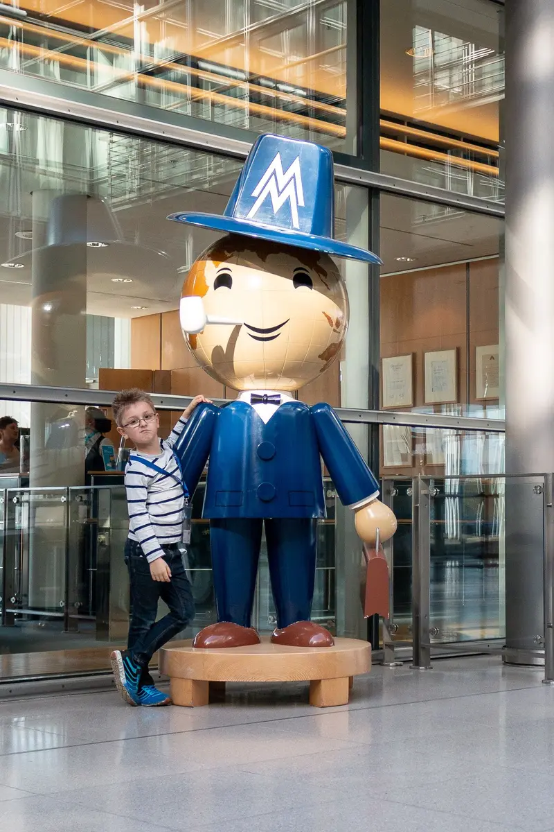Large Corporate Mascot Statue with Visitor in Modern Glass-Walled Architectural Space