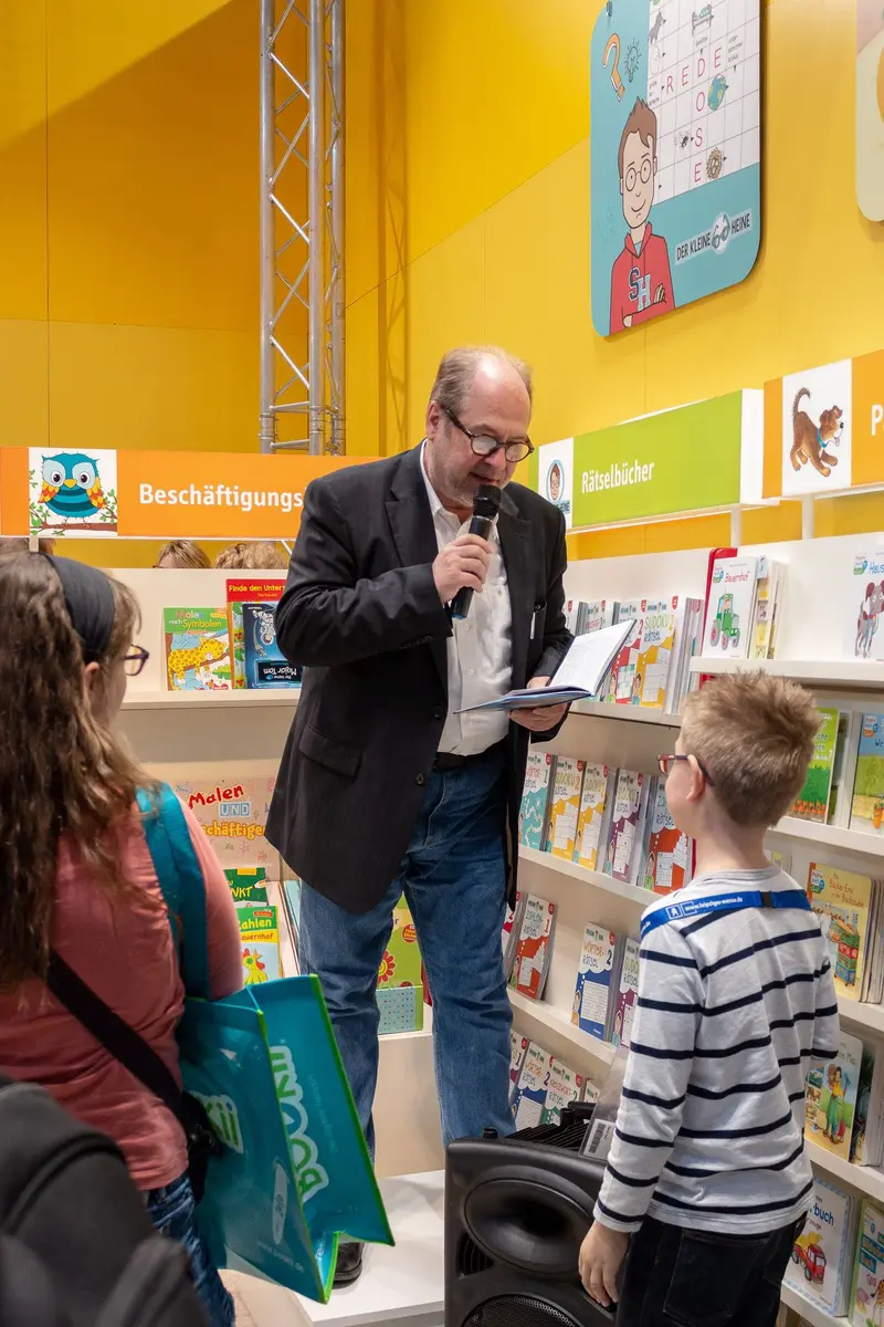Librarian Presenting Books to Young Students in Colorful Reading Space