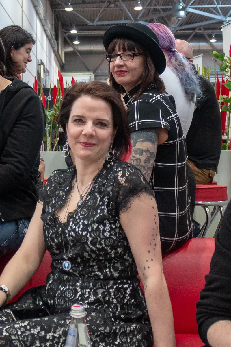 Two Women in Checked and Lace Attire at Indoor Event