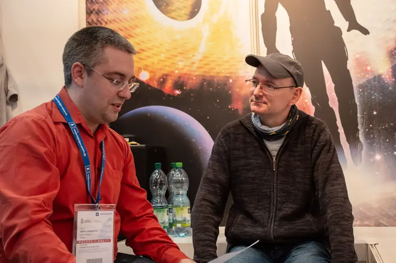 Two Men Conversing at Space-Themed Conference or Exhibition Event