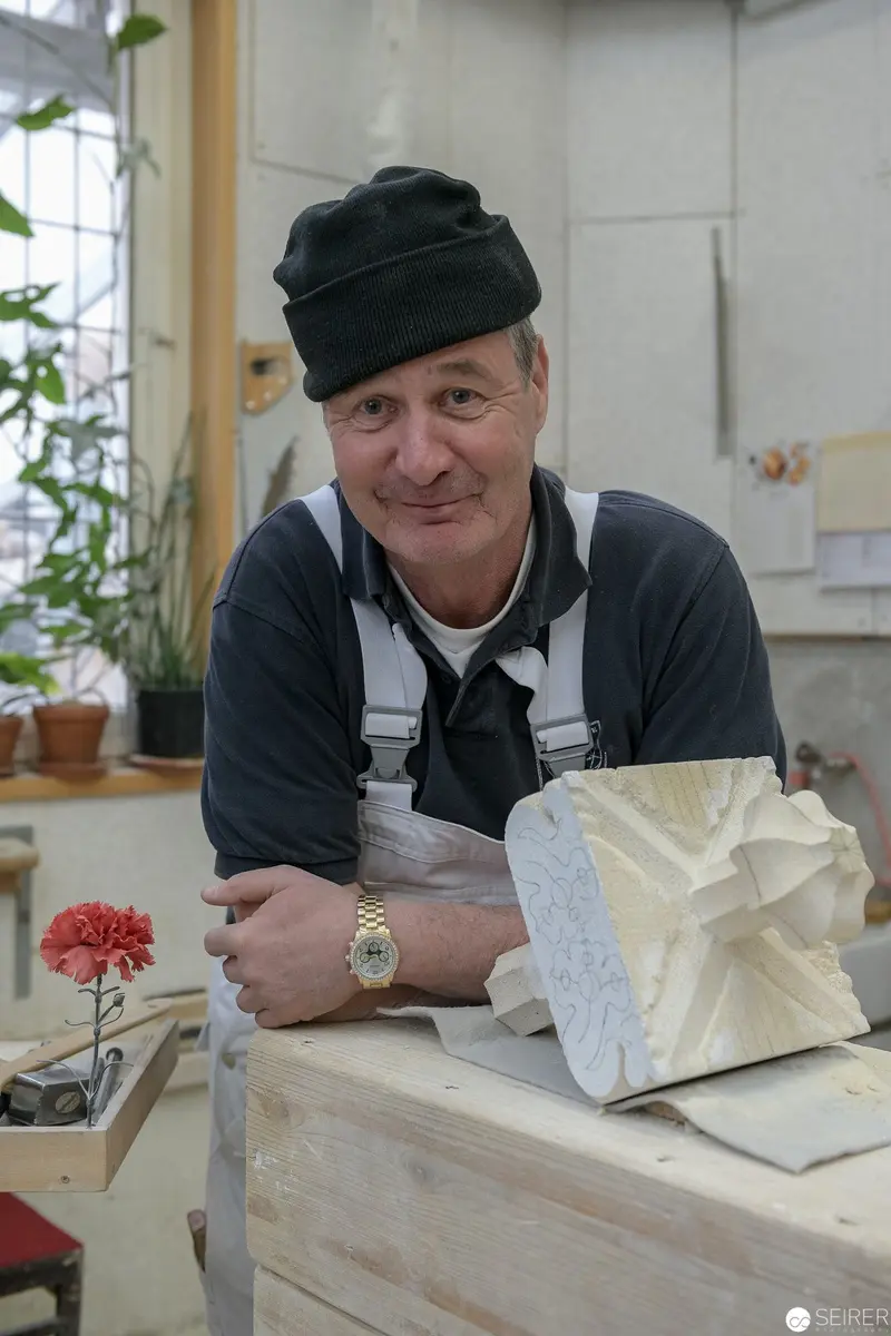 Stonemason at St. Stephan's Cathedral Workshop Wearing Black Cap and Overalls