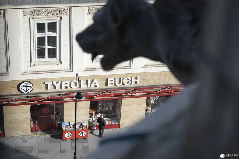 Tyrolia Buch Storefront with Statue Silhouette in Foreground