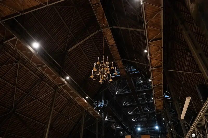 Ornate Chandelier Suspended in Dramatic Industrial Cathedral Ceiling Space