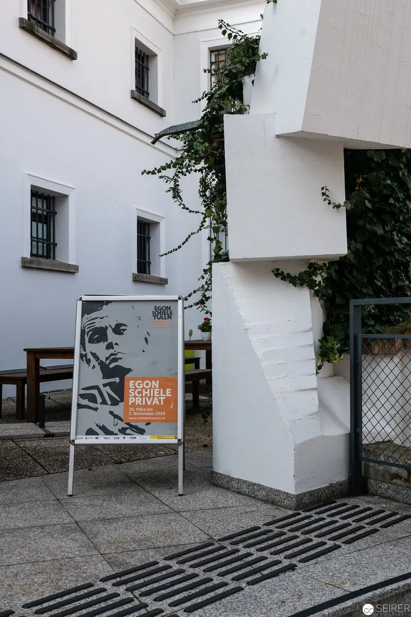 Poster Advertisement Mounted on White Building with Climbing Vegetation