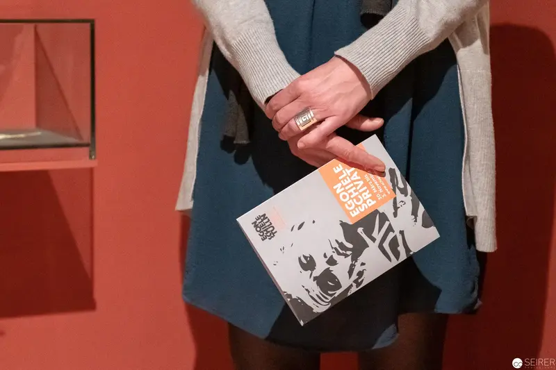 Hand Holding Book with Graphic Cover Against Dark Blue Skirt