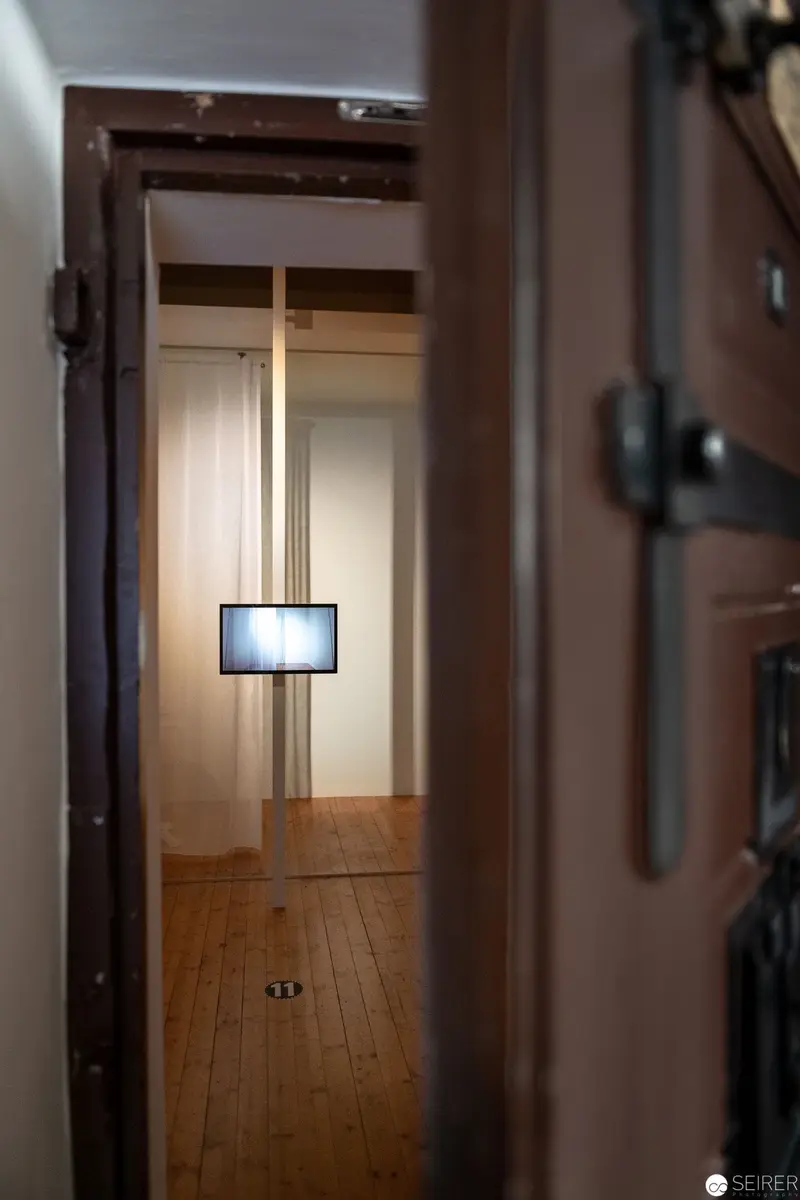 Minimalist Interior with Suspended Illuminated Screen in Wooden Hallway