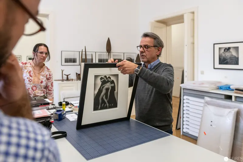 Art Conservator Examining Framed Photographic Print in Studio Setting