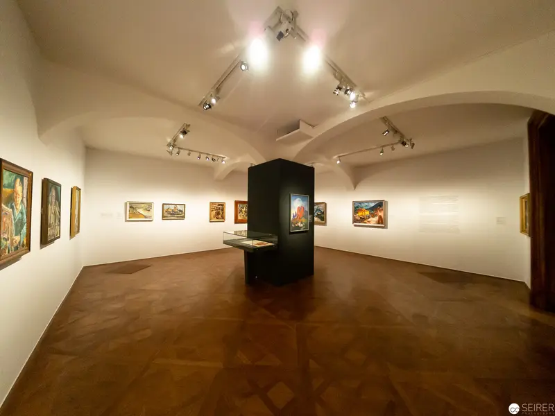 Gallery Interior with Curved Walls and Central Display Featuring Landscape Paintings