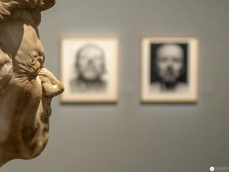 Sculptural Fragment with Blurred Portraits in Gallery Setting