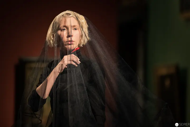 Veiled Performance: Haunting Dramatic Portrait with Black Fabric and Contemplative Gesture