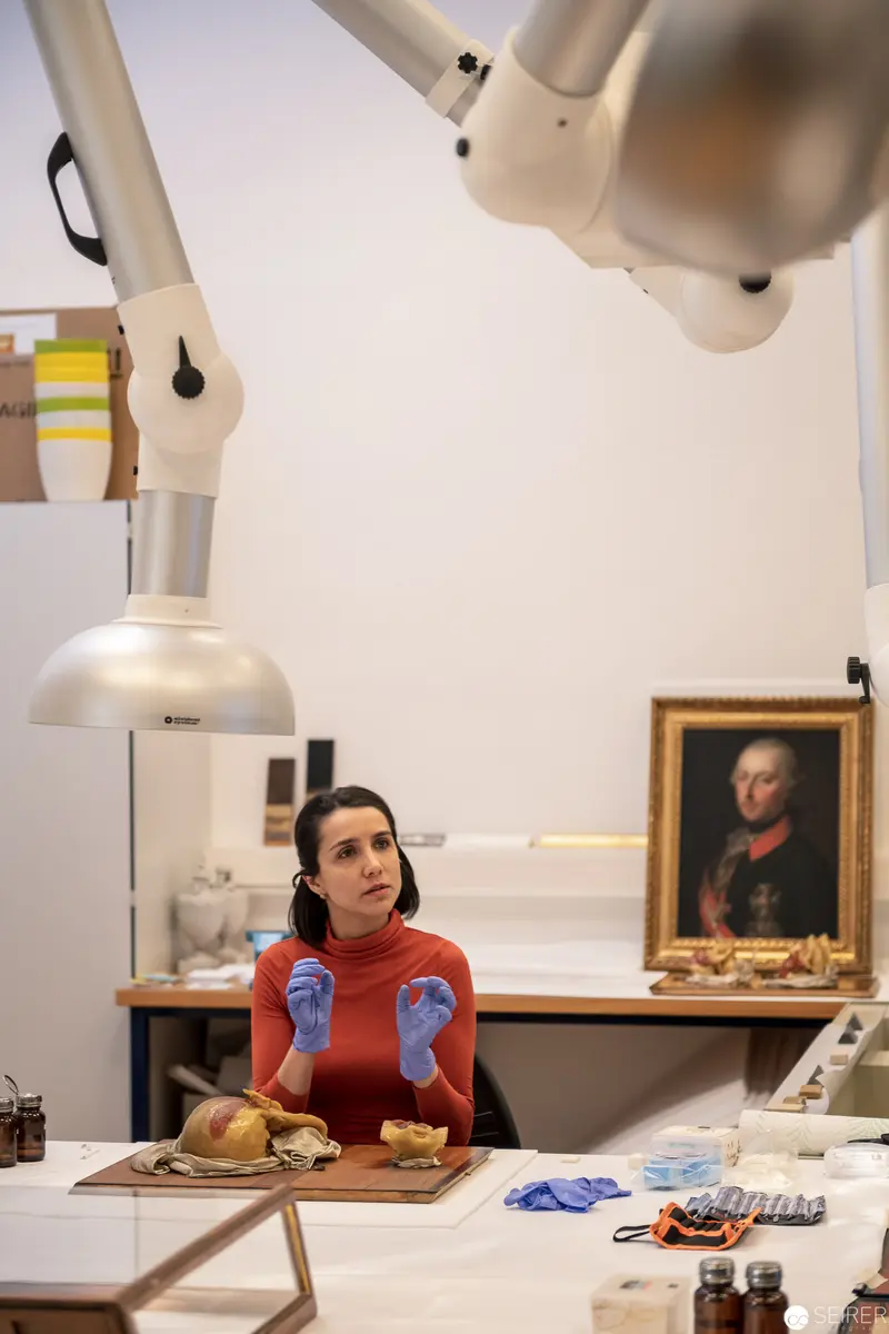 Art Conservator in Red Sweater Examining Historical Artifact with Scientific Precision