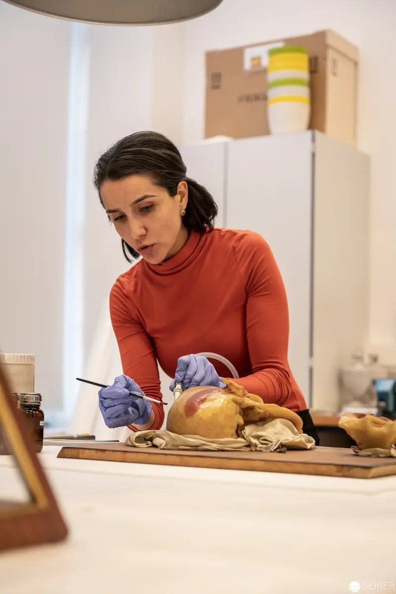 Woman in Red Sweater Preparing Culinary Specimen with Careful Precision