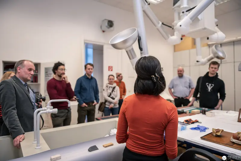 Research Laboratory Seminar with Participants Gathered Around Technical Workstation