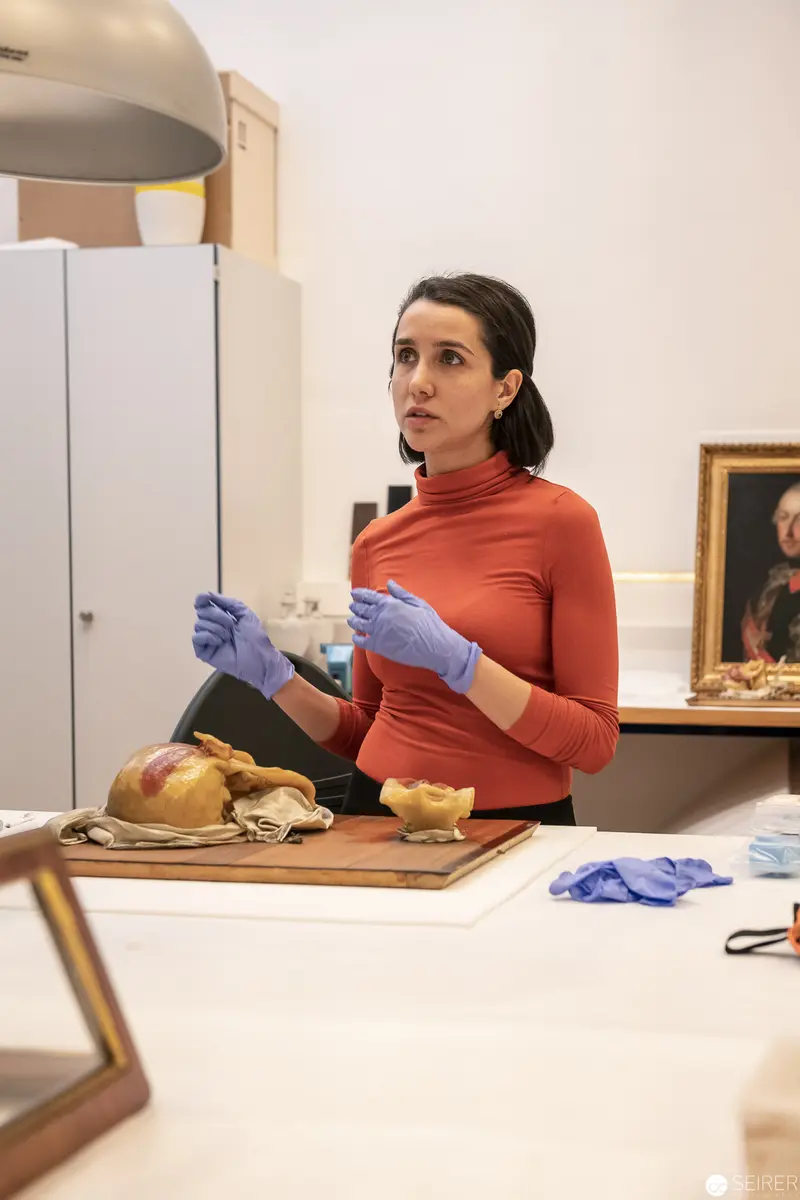 Forensic Scientist in Coral Turtleneck Examines Archaeological Specimens