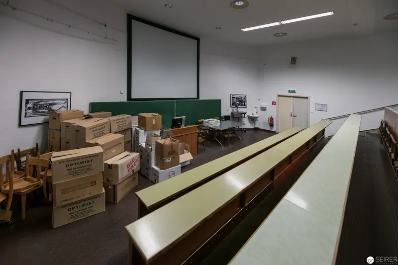 University Storage Room: Cardboard Boxes and Classroom Furniture in Transitional Space