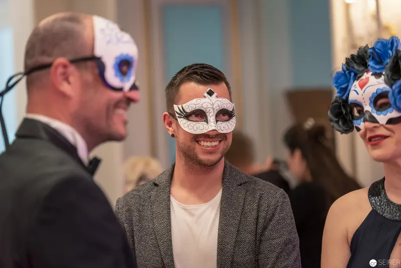 Masked Guests in Elegant Conversation at Formal Masquerade Event