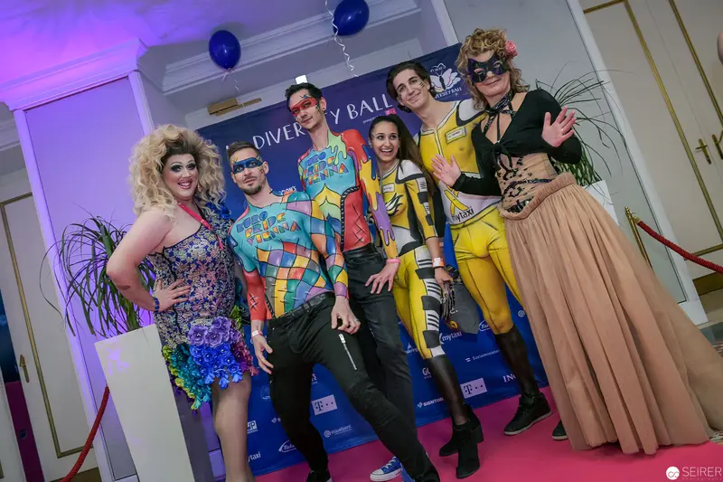 Diverse Ball 2024: Six Costumed Performers Posing on Magenta-Lit Pink Carpet