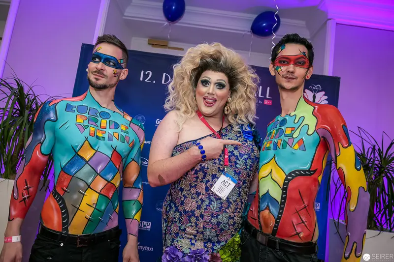 Colorful Body Art and Drag Performance at Social Event with Masked Performers