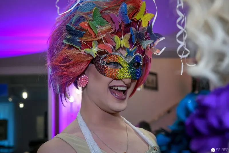 Vibrant Butterfly Masquerade: Performer in Kaleidoscopic Mask and Colorful Hairstyle