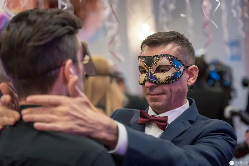 Masked Gentleman in Formal Attire Embracing Colleague at Elegant Event