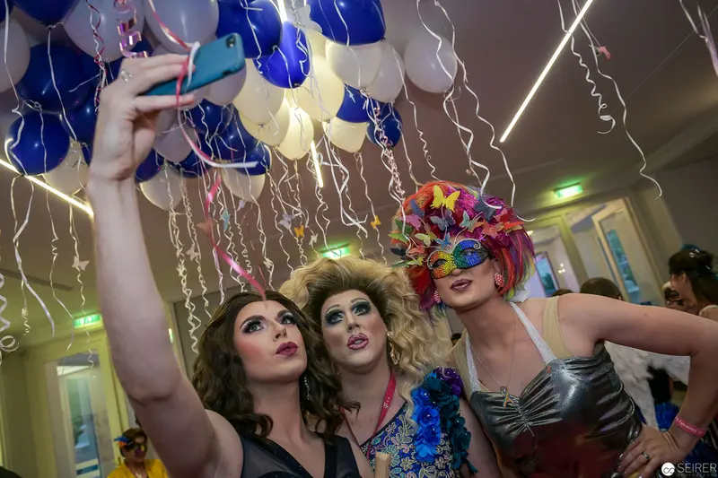 Drag Queens Take Selfie Amid Festive Balloon Celebration with Vibrant Costumes
