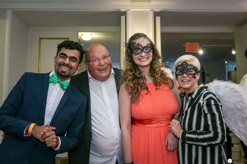 Masked Celebration: Four Guests in Festive Attire at Formal Event
