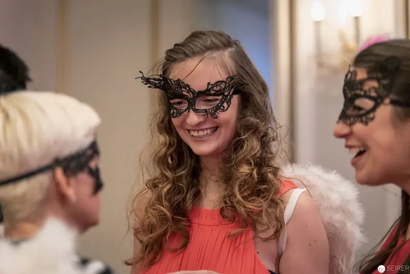 Masquerade Party: Young Women in Decorative Lace Masks Sharing Joyful Moment