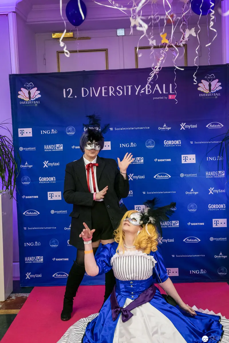 Masked Performers at 12th Diversity Ball Pose on Blue-Backed Promotional Stage