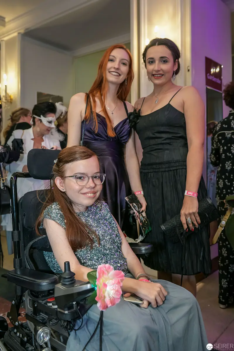 Three Women at Formal Event, One in Wheelchair Wearing Sparkling Dress