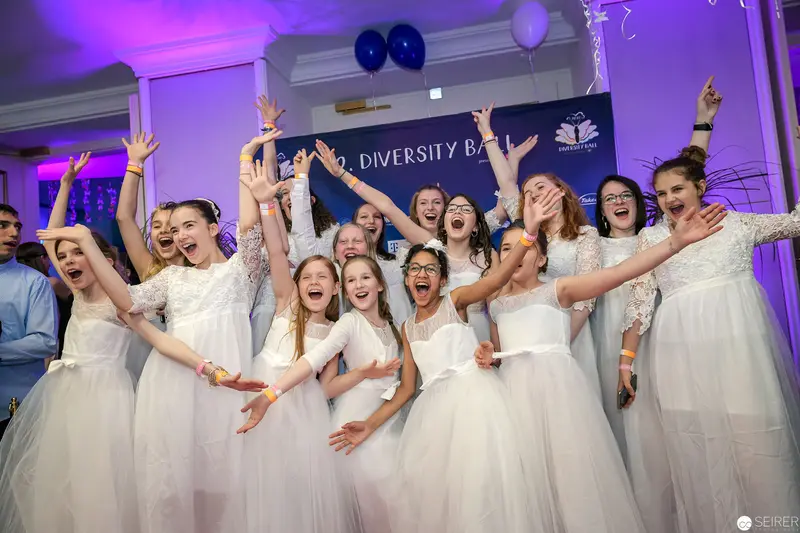 Jubilant Young Performers in White Dresses at Diversity Ball Celebration
