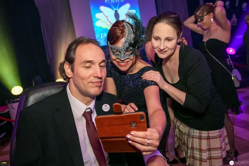 Masked Reveler Takes Selfie with Colleagues at Festive Evening Event