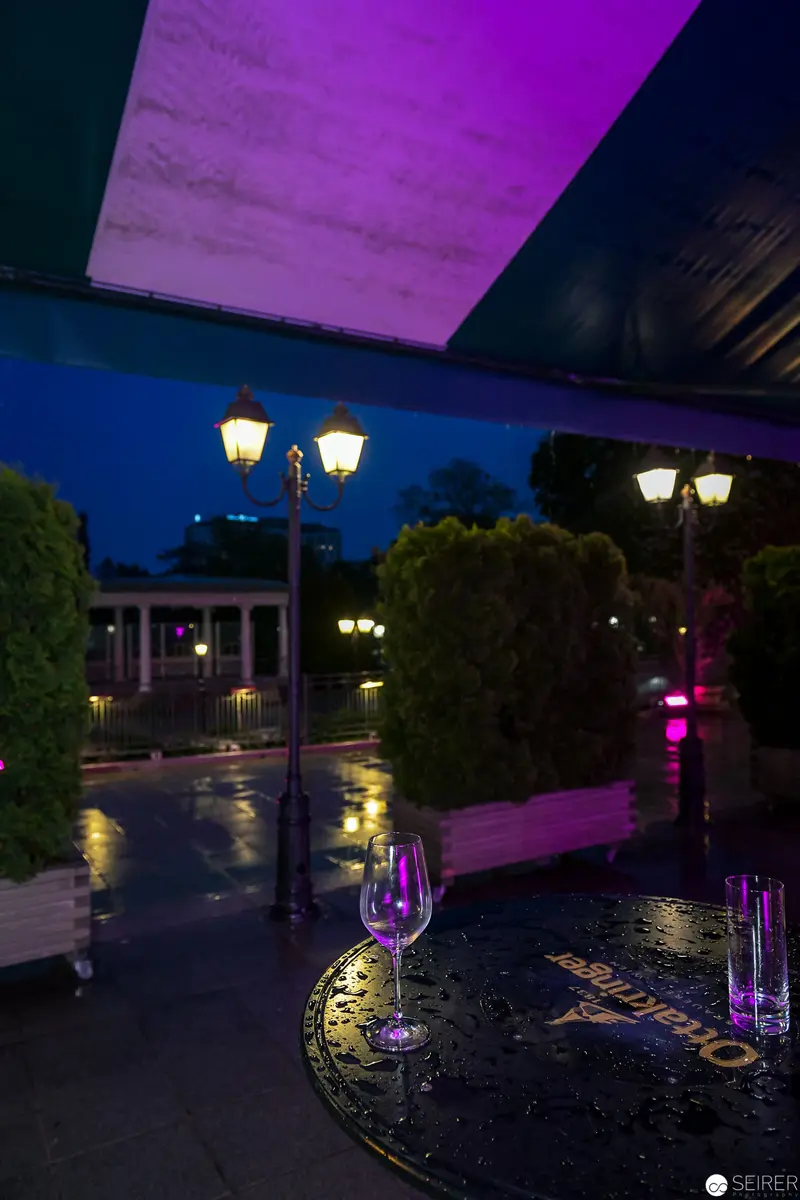 Nocturnal Urban Terrace with Illuminated Wine Glasses and Street Lamps